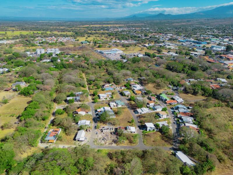 Vista aérea del condominio con sus casas, la ciudad de Liberia y las montañas de Guanacaste al fondo