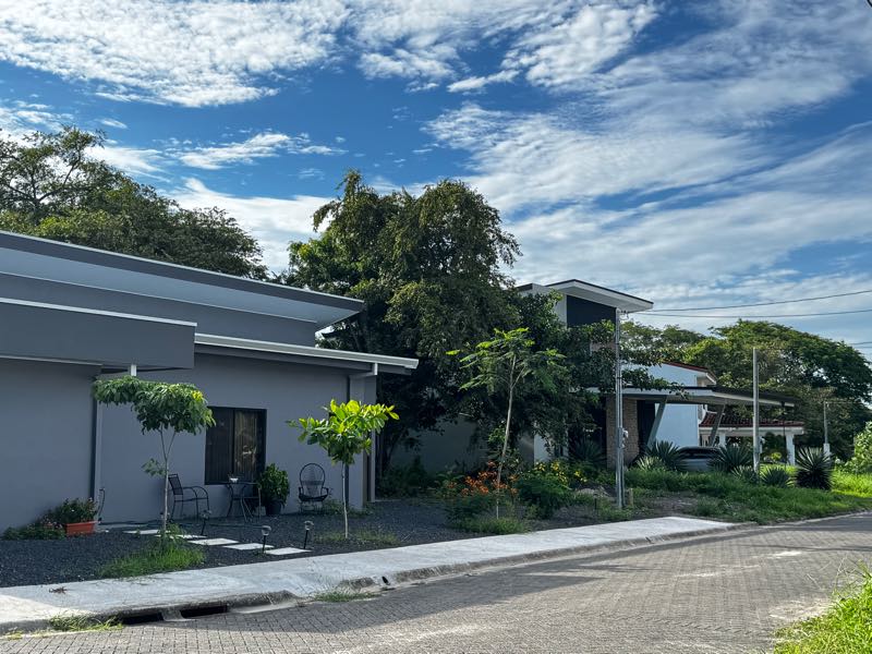 Casas de una planta ya construidas, con jardín, frente a una calle adoquinada del condominio